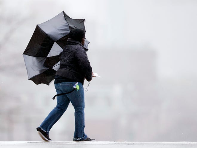 A women's umbrella is upset by the wind during the rainstorm Tuesday in Philadelphia. A slow-moving storm churned through the Northeast early Tuesday, bringing heavy rains and strong wind to coastal areas, at least half a foot of heavy, wet snow inland and a wintry mix to the New England states.