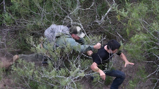 A U.S. Border Patrol agent tries to tackle an undocumented immigrant in dense underbrush on Sept. 9, 2014, near Falfurrias. He missed, but the immigrant was later caught by a fellow agent. Some worry that the president’s executive order will only encourage more illegal immigration.