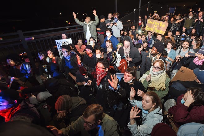 Protesters and police officers face off on a pedestrian bridge over Interstate 80 shortly after protesters shut down traffic in both directions in response to police killings in Missouri and New York in Berkeley, Calif., Monday, Dec. 8, 2014. Hundreds of people marched through downtown Berkeley Monday.
