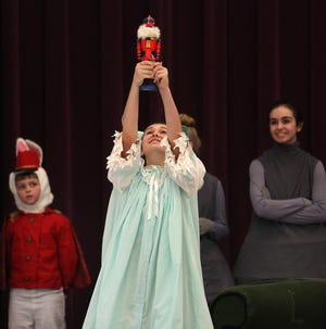 Springfield Ballet Co. dancer Olivia Pennell, playing Clara, holds up a Christmas gift right before the Nutcracker prince shows up in the ballet “The Nutcracker.”