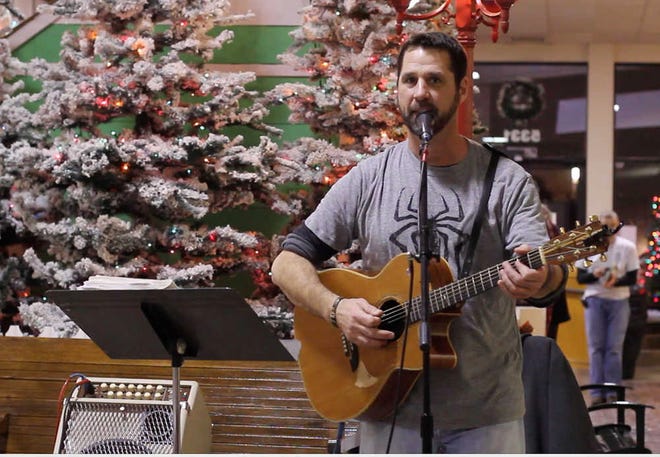 Musician Kyler Carpenter plays acoustic Christmas songs during a recent First Friday Artwalk event at Fairlawn Plaza in Topeka. Carpenter especially enjoys playing music for children at the Topeka and Shawnee County Public Library, where he works.