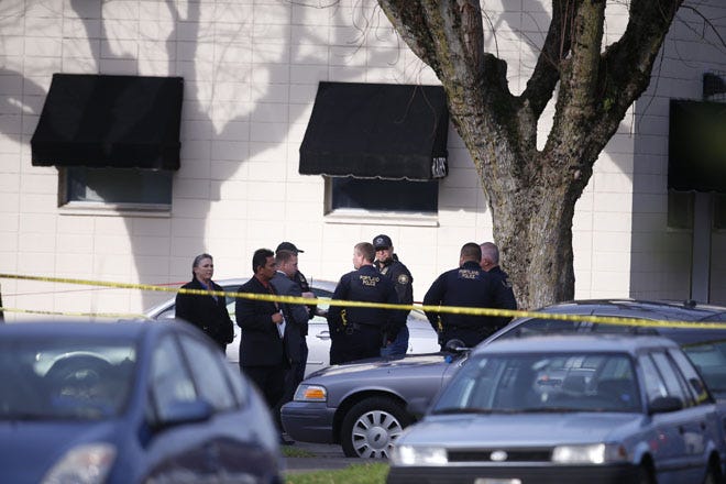 Police gather outside Rosemary Anderson High School in north Portland, Ore., where a shooting occurred today. A shooter wounded two boys and a girl outside the high school in what may be a gang-related attack, police said.
