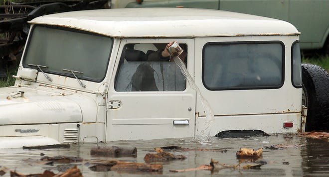 An employee of Mudrak Custom Cruisers bails out a jeep that will be pulled from floodwaters in Sonoma, Calif., Thursday, Dec. 11, 2014. A powerful storm churned down the West Coast Thursday, bringing strong gales and much-needed rain and snow that caused widespread blackouts in Northern California and whiteouts in the Sierra Nevada. Sonoma County authorities recommended hundreds of people to evacuate the lowest lying areas near the Russian River, which is projected to start overflowing overnight. (AP Photo/The Press Democrat, Kent Porter)