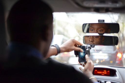 UberPOP driver Anthony Loussala-Dubreas, 24, of Paris, turns on his smartphone in his car in Paris, Friday, Dec. 12, 2014. A French court on Friday ordered Uber to withdraw from its mobile app to French users "all mention suggesting it is legal" for Uber's drivers to act like taxis — that is, driving around and waiting for clients. But the court did not ban the popular ride-hailing service. (AP Photo/Bastien Inzaurralde)