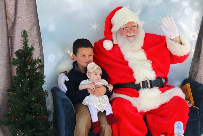 Six-year-old Anthony Jacob holds his sister, 3-month-old Katelyn, while they pose for a photo with Santa Claus at Palm Coast’s annual Starlight Holiday Event on Saturday at Central Park at Town Center.