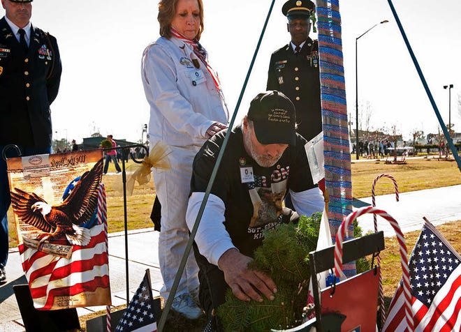 Corey Dickstein/Savannah Morning News  Linda Lamie looks on as her husband Eugene places a holiday wreath at the base of the crape myrtle dedicated to the memory of their son, fallen U.S. Army Sgt. Gene Lamie, at Fort Stewart's Warriors Walk early Saturday afternoon. For the eighth year Fort Stewart and local non-profit Wreaths for Warriors Walk, Inc. held its Wreaths for Warriors Walk ceremony in which wreaths were placed at the base of each of the 468 trees dedicated to soldiers killed in Iraq or Afghanistan since 2003.