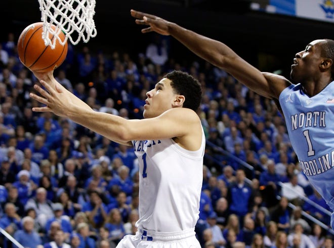 Kentucky's Devin Booker, left, shoots under pressure from North Carolina's Theo Pinson Saturday during the top-ranked Wildcats' 84-70 win. THE ASSOCIATED PRESS
