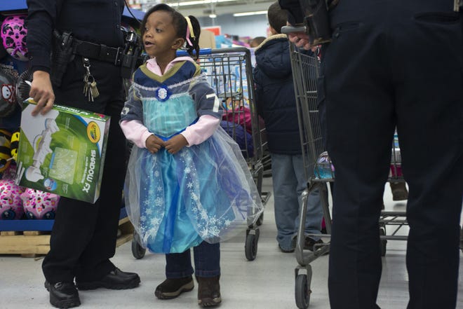Marjaz Woodruff, 6, of Akron, wears her new Elsa gown while shopping with Akron Police Officer Jamie McKinley, during the Summit County Shop with a Cop program Saturday at the Stow Wal-Mart. (?Erin LaBelle/special to the Akron Beacon Journal)