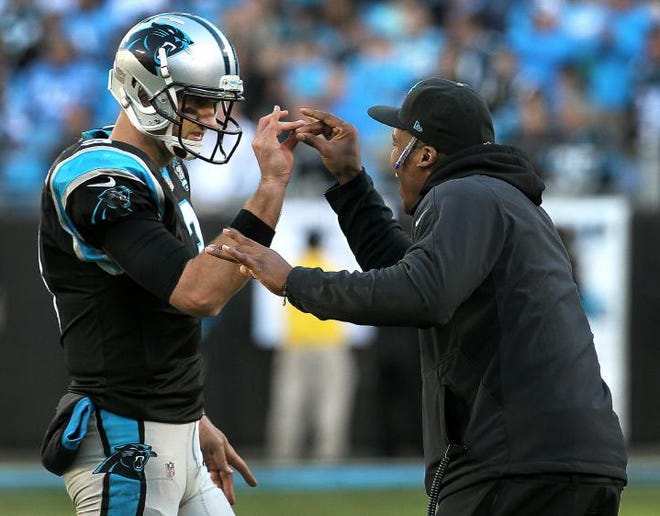 Panthers quarterback Derek Anderson, left, celebrates with injured quarterback Cam Newton after throwing a touchdown pass. Anderson’s starting record with the Panthers improved to 2-0 — both wins against Tampa Bay — and Carolina is set to take first place in the NFC South if New Orleans loses to Chicago on Monday.