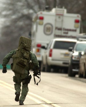 A police officer runs up Washington Avenue toward Garfield where the command station is during a standoff in Souderton Monday morning.