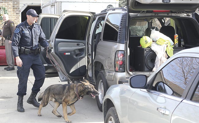 Michigan State Police Trooper Jereme Miller and his K-9 Dakota search for drugs during a raid Monday at 69835 Deer Road.
