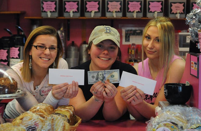 Marylou's manager Victoria Grandy, Deanna Moreland and Alex Doucette, left to right, hold some of the envelopes that were dropped off at the Hyannis coffee shop by a mystery man. The man handed the employees envelopes with $100 bills inside when he stopped at Marylou's on Saturday. Merrily Cassidy/Cape Cod Times