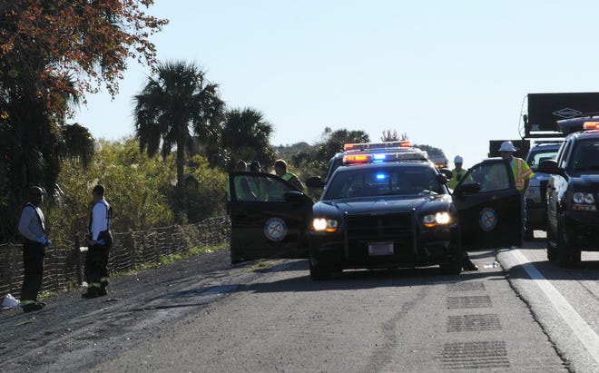 Florida Highway Patrol homicide investigators and rescue personnel survey the scene of a car submerged in a marshy area along Interstate 4 near Deltona. Two bodies were found in the car.
