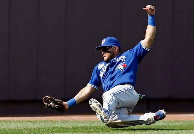 In this July 27, 2014, file photo, Toronto Blue Jays left fielder Melky Cabrera makes a sliding catch of Yankees' Ichiro Suzuki's ninth-inning flyout to deep left field in a baseball game at Yankee Stadium in New York. The Chicago White Sox have finalized a $42 million, three-year contract with free-agent outfielder Cabrera.