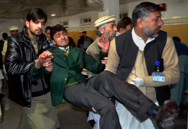 Pakistani volunteers carry a student injured in the shootout at a school under attack by Taliban gunmen, at a local hospital in Peshawar, Pakistan, on Tuesday, Dec. 16, 2014. Taliban gunmen stormed a military school in the northwestern Pakistani city, killing and wounding dozens, officials said, in the latest militant violence to hit the already troubled region.
