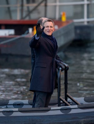 Actor Daniel Craig waves at onlookers as he films a scene with Rory Kinnear, back obscured, on a canal for the new James Bond movie, "SPECTRE," in London, on Tuesday, Dec. 16, 2014. Filming is underway on "SPECTRE" despite the leak of a draft script in a huge hack of material from Sony Pictures.
