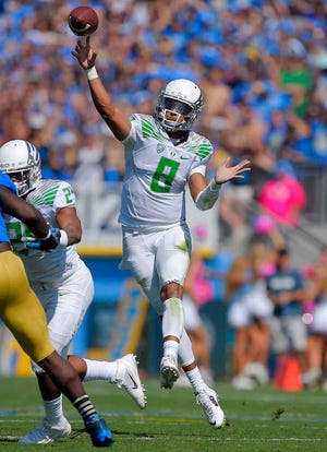 FILE - In this Oct. 11, 2014, file photo, Oregon quarterback Marcus Mariota passes during the first half of an NCAA college football game against UCLA in Pasadena, Calif. The College Football Playoff participants are well represented on The Associated Press All-America team. Heisman winner Marcus Mariota is the first Ducks' quarterback to be an All-American. (AP Photo/Mark J. Terrill, File)