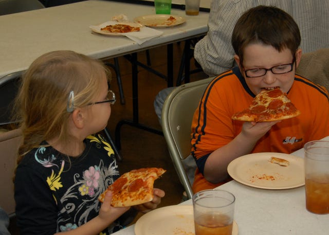 BRIAN MCMAHEN • TIMES RECORD Sunny Barnett, left, watches her big brother, River Barnett, eat another slice of Little Caesars pizza at the Community Rescue Mission in Fort Smith on Monday, Dec. 15, 2014. The Little Caesars Love Kitchen rolled into Fort Smith Monday evening to help feed members of the community. Jeff O’Meara, the Love Kitchen driver, said the Little Caesars Love Kitchen travels across the continental United States and Canada meeting the needs of the hungry, the homeless and the low-income families in each area they visit. Sunny and River are the children of Anna Barnett of Fort Smith. 
 BRIAN MCMAHEN • TIMES RECORD Rebecca Moon, from left, and Sarah Childs, both volunteers from F.A.I.T.H. Homeschool, and Emma Matlock prepare to hand out Little Caesars pizza at the Community Rescue Mission in Fort Smith on Monday, Dec. 15, 2014. Jeff O’Meara, the Love Kitchen driver, said the Little Caesars Love Kitchen travels across the continental United States and Canada meeting the needs of the hungry, the homeless and the low-income families in each area they visit. 
 BRIAN MCMAHEN • TIMES RECORD Alicia McDaniel, General Manager at Little Caesars Pizza in Fayetteville, carries pizza to the Community Rescue Mission in Fort Smith on Monday, Dec. 15, 2014. The Little Caesars Love Kitchen rolled into Fort Smith Monday evening to help feed members of the community. Jeff O’Meara, the Love Kitchen driver, said the Little Caesars Love Kitchen travels across the continental United States and Canada meeting the needs of the hungry, the homeless and the low-income families in each area they visit.