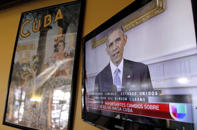 President Barack Obama is shown on a television screen with Spanish captions as a Spanish language television network shows his speech live inside a Cuban coffee shop, Wednesday, Dec. 17, 2014, in Union City, N.J. Obama announced the re-establishment of diplomatic relations and an easing in economic and travel restrictions on Cuba Wednesday, declaring an end to America's “outdated approach” to the communist island in a historic shift aimed at ending a half-century of Cold War enmity.
