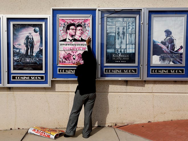 A poster for the movie "The Interview" is taken down by a worker after being pulled from a display case at a Carmike Cinemas movie theater on Wednesday, in Atlanta.