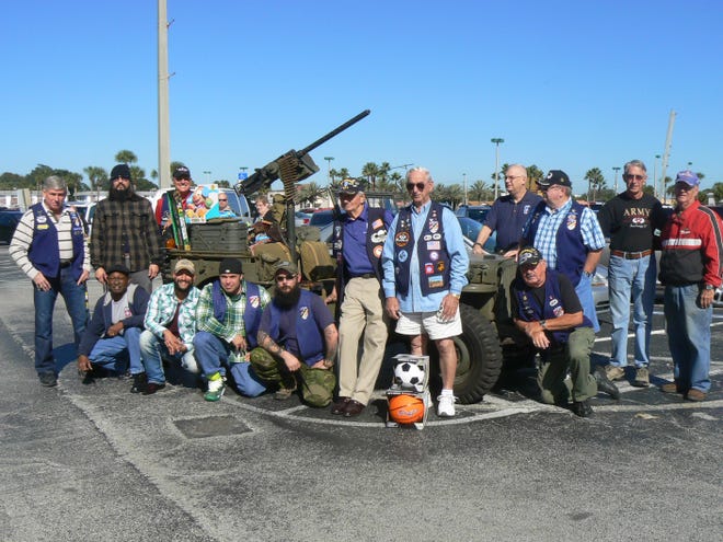 Members of the Greater Daytona Chapter of the 82nd Airborne Association gather around a 1945 World War II era jeep filled with gifts for children to be donated to the Toys For Tots program.