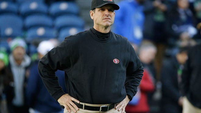 San Francisco 49ers head coach Jim Harbaugh stands on the field before an NFL football game against the Seattle Seahawks, Sunday, Dec. 14, 2014, in Seattle. (AP Photo/Elaine Thompson)