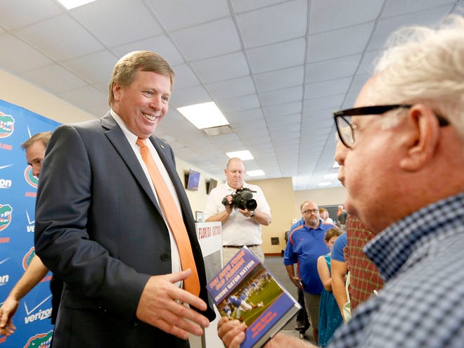 New head football coach Jim McElwain is given a book after the press conference in the Norm Carlson Press Box at Ben Hill Griffin Stadium in this Dec. 6, 2014 file photo.
