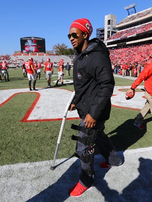 Injured Georgia running back Todd Gurley, who is expected to miss the remainder of the season after injuring his knee last week against Auburn, walks the end zone on a crutch and a leg brace while his team prepares to play Charleston Southern in an NCAA college football game, Saturday, Nov. 22, 2014, in Athens, Ga. (AP Photo/Atlanta Journal-Constitution, Curtis Compton)