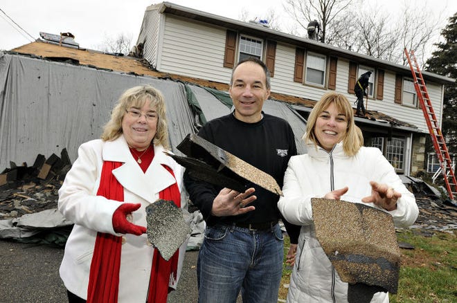 Left to right, Joyce Palermo; Erich Uhlenbrock and his wife Kristine toss away old shingles from their Northampton home Friday as workers from Kanga Roof, a division of A. Brooks Construction Inc.,  install a free new roof on home. It's a tradition of the company for the holidays for a number of years.