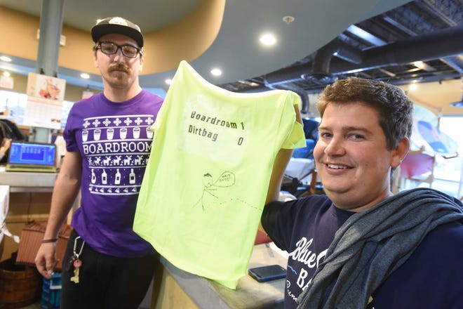 The Boardroom Pub and Grub co-owners, Bobby Nabors, right, and Rhys Sharp hold a t-shirt on Friday that Nabors’ wife made to commemorate the purse-snatching event.