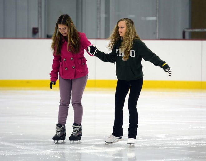 Kaylyn Clohecy, 14, left, gets help from her friend Ashley Weekly, 14, both from Montville, as they skate Saturday during the opening day of the Rose Garden Ice Rink in Norwich.
