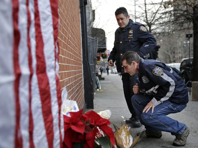 Police officers leave candles at an impromptu memorial near the site where two New York City police officers were killed in the Brooklyn borough of New York, Sunday, Dec. 21, 2014. Police say Ismaaiyl Brinsley ambushed officers Rafael Ramos and Wenjian Liu in their patrol car in broad daylight Saturday, fatally shooting them before killing himself inside a subway station.