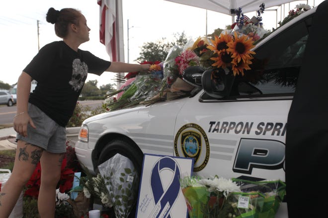 Cynthia Martinez, 23 of Tarpon Springs, leaves flowers at a memorial for a slain Tarpon Springs police officer in Tarpon Springs, Fla. on Sunday, Dec. 21, 2014. The Tarpon Springs Police Department identified the fallen officer as 45-year-old Charles Kondek, a 17-year veteran of the local police department. Originally from New York, Kondek had previously served on the New York City Police Department for more than five years, authorities said. (AP Photo/Tampa Bay Times, Monica Herndon)