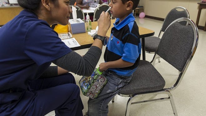 Joey Martin, 5, a kindergarten student at Tom Green Elementary in the Hays school district, gets a flu mist vaccination from nurse Catherine Calimlim in Buda in November. Students were able to get a mist vaccination instead of a traditional shot.