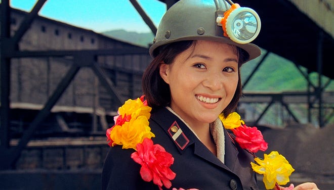 In this file image made out of the film "Comrade Kim Goes Flying," Comrade Kim Yong Mi, played by Han Jong Sim, smiles as she wears a coal miner's helmet.