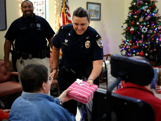 Gainesville Police Department Lt. Whitney Stout hands a Christmas gift to Joyce Kevas during GPD's Silver Santa event at the Easter Seals Florida Altrusa House in northwest Gainesville on Monday.