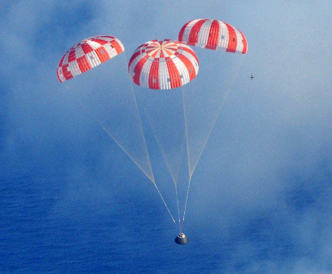 NASA’s Orion crew module descends to the Pacific Ocean under its three main parachutes as part of the Orion program’s first exploration flight test Dec. 5.