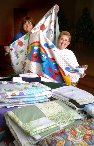 Lisa Eberhart, left, helps tie blankets created by Millie Humphries. The Dorcas Circle at Grace United Methodist Church have made more than 200 blankets in 2014 to donate to people in need. Eberhart and Humphries are both members of the group.