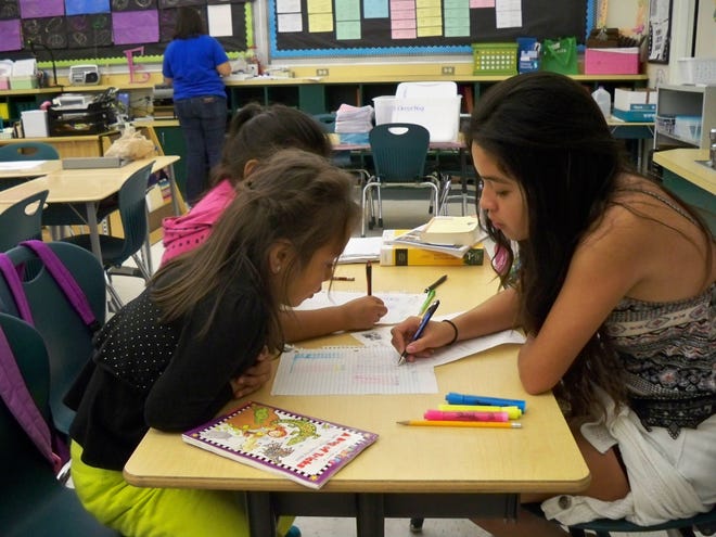 Gloria Martinez, a first-grade ESOL student, receives some reading help from Yosabet Ruentes, a junior at DeLand High School and a member of Epsilon Alpha Chi.