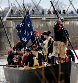 As people watch from a bridge, George Washington, played by John Godzieba, second right, holds onto his hat as he and his troops cross the Delaware River during the 62nd annual re-enactment of Washington's daring Christmas 1776 crossing of the river Thursday in Washington Crossing. (Mel Evans/Associated Press)
