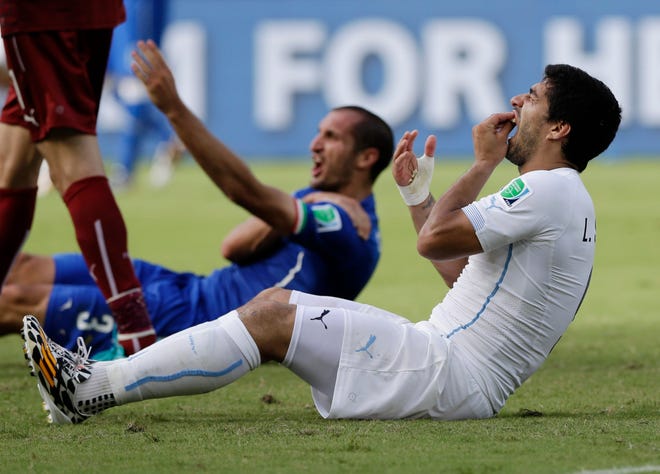 FILE - In this June 24, 2014, file photo, Uruguay's Luis Suarez holds his teeth after running into Italy's Giorgio Chiellini's shoulder during a group D World Cup soccer match in Natal, Brazil. Perhaps odder things happened in sports in 2014, but for sheer audacity, and on a global stage no less, the bite by Suarez takes the (temporary porcelain) crown. (AP Photo/Ricardo Mazalan, File)