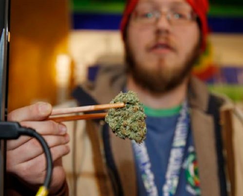 Sales associate Matt Hart uses a pair of chopsticks to hold a bud of Lemon Skunk, the strain of highest potency available at the 3D Dispensary Dec. 19 in Denver. While polls show more voters favoring the legalization of marijuana, law enforcement officials in Nebraska and Oklahoma have asked the U.S. Supreme court to end Colorado's legalized pot experiment.
