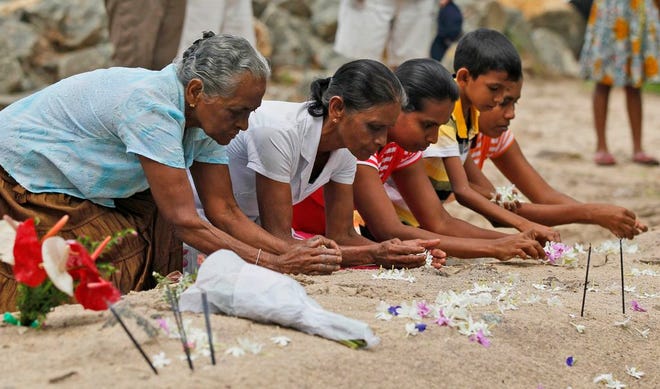 Sri Lankan tsunami survivors pay their respect at a mass grave of 591 train passengers which was hit by 2004 tsunami in Peraliya, Sri Lanka, Friday, Dec. 26, 2014. In Sri Lanka the train 591, which was tossed up by the waves and the charred images of which became an icon of the disaster, carried some survivors, relatives of the dead and the guard who was on duty 10 years ago, stopped at the disaster site for a remembrance of the dead. The train including the original locomotive and five carriages was decorated with Buddhist flags and Buddhist chanting was played through the journey. (AP Photo/Eranga Jayawardena)