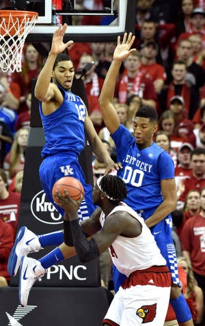 Kentucky's Karl-Anthony Towns, top left, and Marcus Lee, top right, contest a shot by Louisville's Montrezl Harrell during the first half of an NCAA college basketball game Saturday Dec. 27, 2014, in Louisville, Ky. Kentucky won 58-50. (AP Photo/Timothy D. Easley)