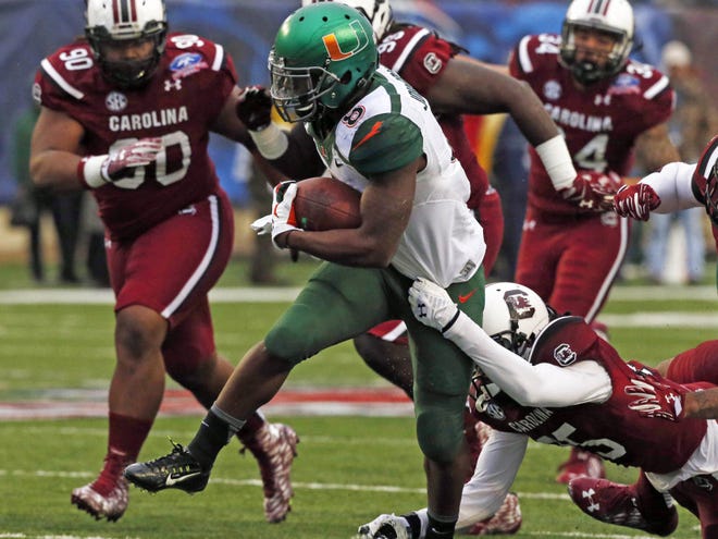 Miami running back Duke Johnson (8) breaks away from a tackle attempt by South Carolina safety Kadetrix Marcus in the first half of the Independence Bowl NCAA college football game in Shreveport, La., Saturday.