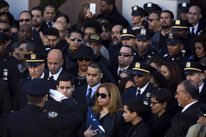 Flanked by her sons Justin, left, and Jaden, Maritza Ramos holds the flag presented to her at the funeral Saturday of her husband, Officer Rafael Ramos, in Queens, N.Y.