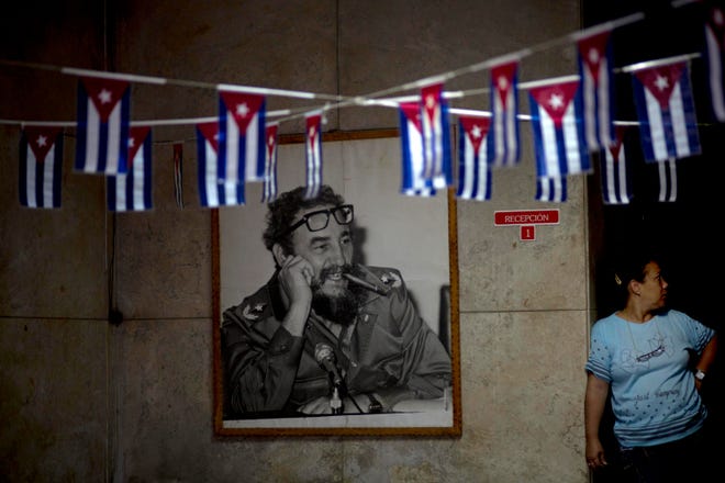 A photograph Fidel Castro hangs in a municipal building where miniature Cuban flags decorate the entrance in Havana Friday.