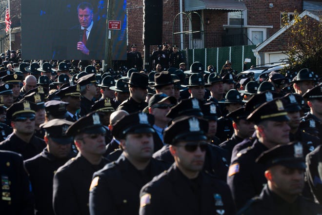 Police officers turn their backs as New York City Mayor Bill de Blasio speaks at the funeral of New York city police officer Rafael Ramos in the Glendale section of Queens, Saturday, Dec. 27, 2014, in New York. Ramos and his partner, officer Wenjian Liu, were killed Dec. 20 as they sat in their patrol car on a Brooklyn street. The shooter, Ismaaiyl Brinsley, later killed himself. (AP Photo/John Minchillo)