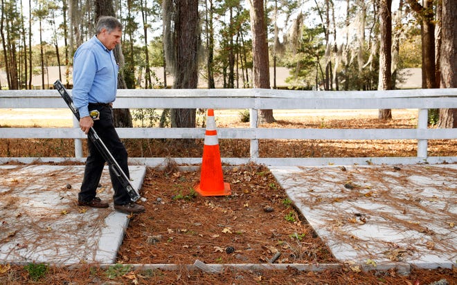 Terry Martin-Back walks a sidewalk project along NW 98th Street pointing out its flaws during a media interview Thursday, December 11, 2014. Pictured here Martin-Back approaches a section of missing sidewalk. He claims this one section remains incomplete so officials can keep the sidewalk closed.