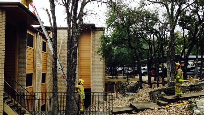 Austin firefighters inspect the charred roof of The Ridge apartment complex in South Austin on Sunday, where an electrical fire displaced about a dozen people.